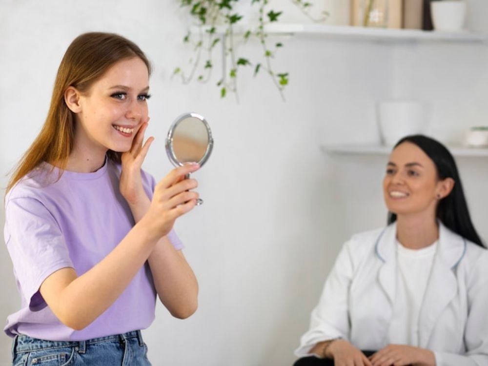 Pele Acneica: Cuidados com a pele do rosto!
imagem de mulher se olhando no espelho, dentro do consultorio medico vendo o resultado do seu rosto, limpo sem acne.