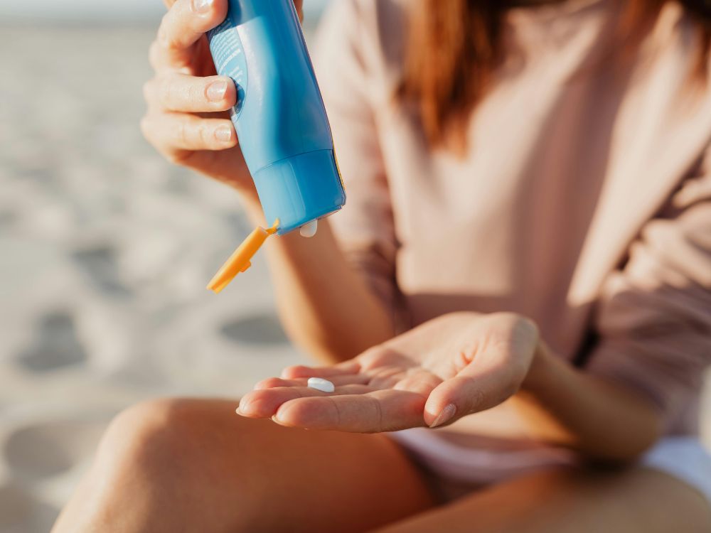 melhores protetores solares com cor
imagem: mulher passando protetor solar na praia